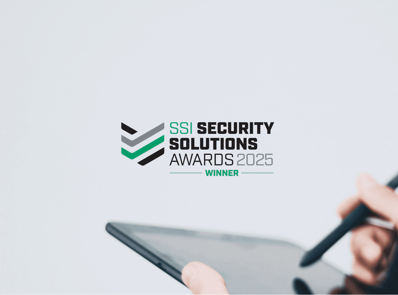 An image showing the SSI Security Solutions Awards 2025 Logo over a background image of two hands holding a tablet