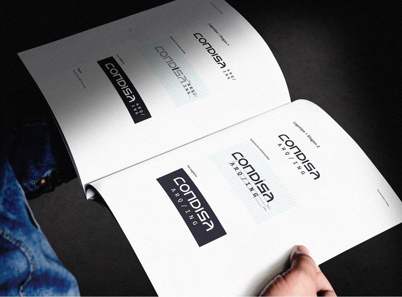 two hands holding the brand book, pages are showing the logotype structure